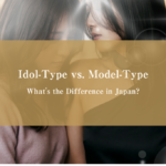 Glamour-style editorial photograph of two Japanese women seated closely together in a luxury hotel setting — one styled with soft idol-type warmth, the other with sleek model-type composure — with faces partially obscured and not individually identifiable