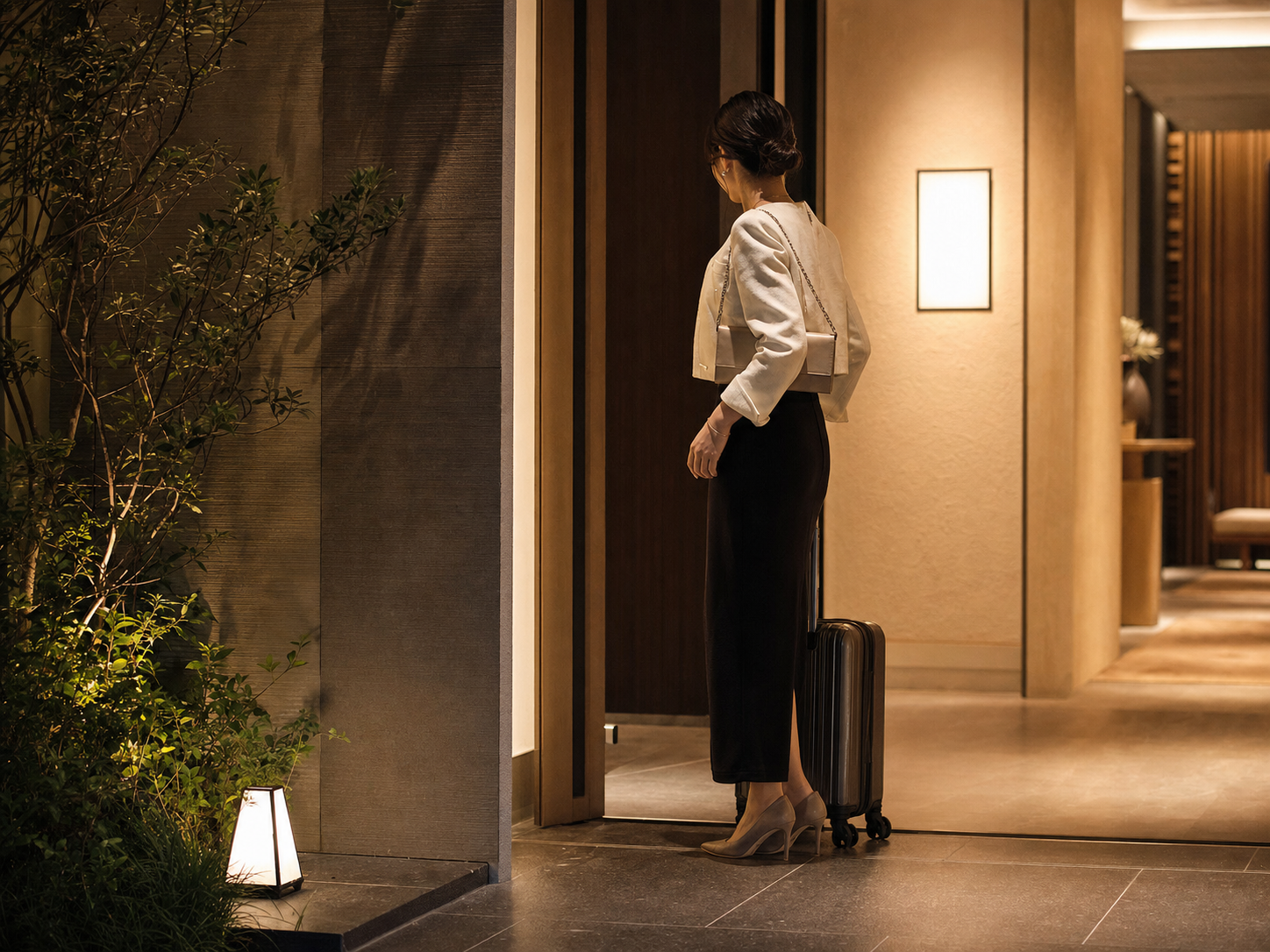 Discreet arrival at a quiet Ginza or Chuo hotel corridor in Tokyo, elegant nighttime hospitality setting